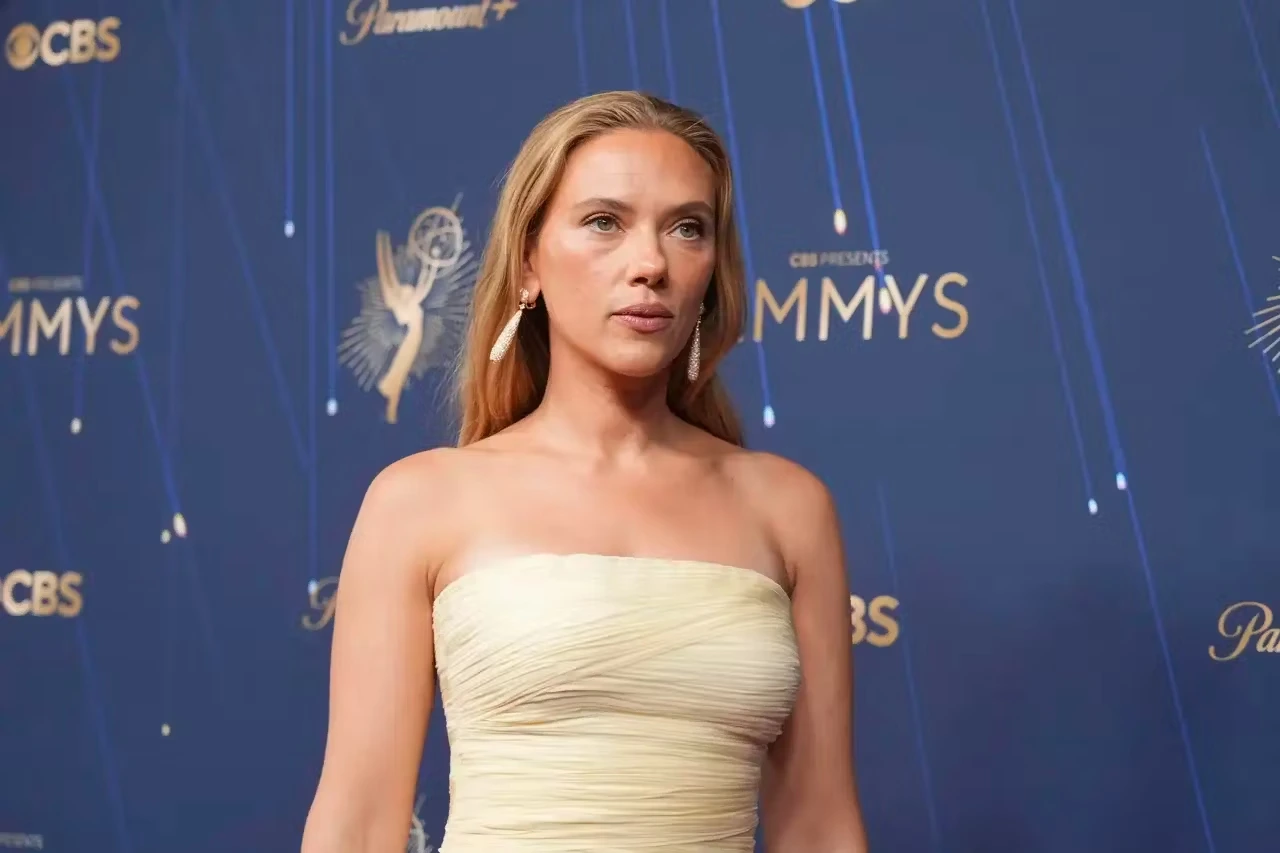 Scarlett Johansson con un vestido claro ante un fondo azul en un evento público